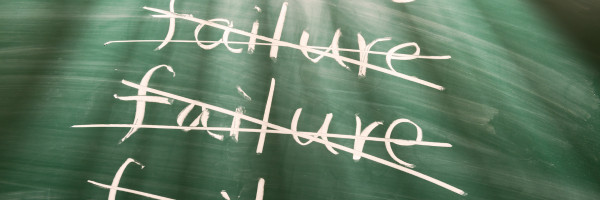 Chalk board with the word "failure" crossed out multiple times and the word "success at the top"
