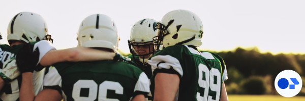 Group of football players, suited up in green jerseys and white helmets.